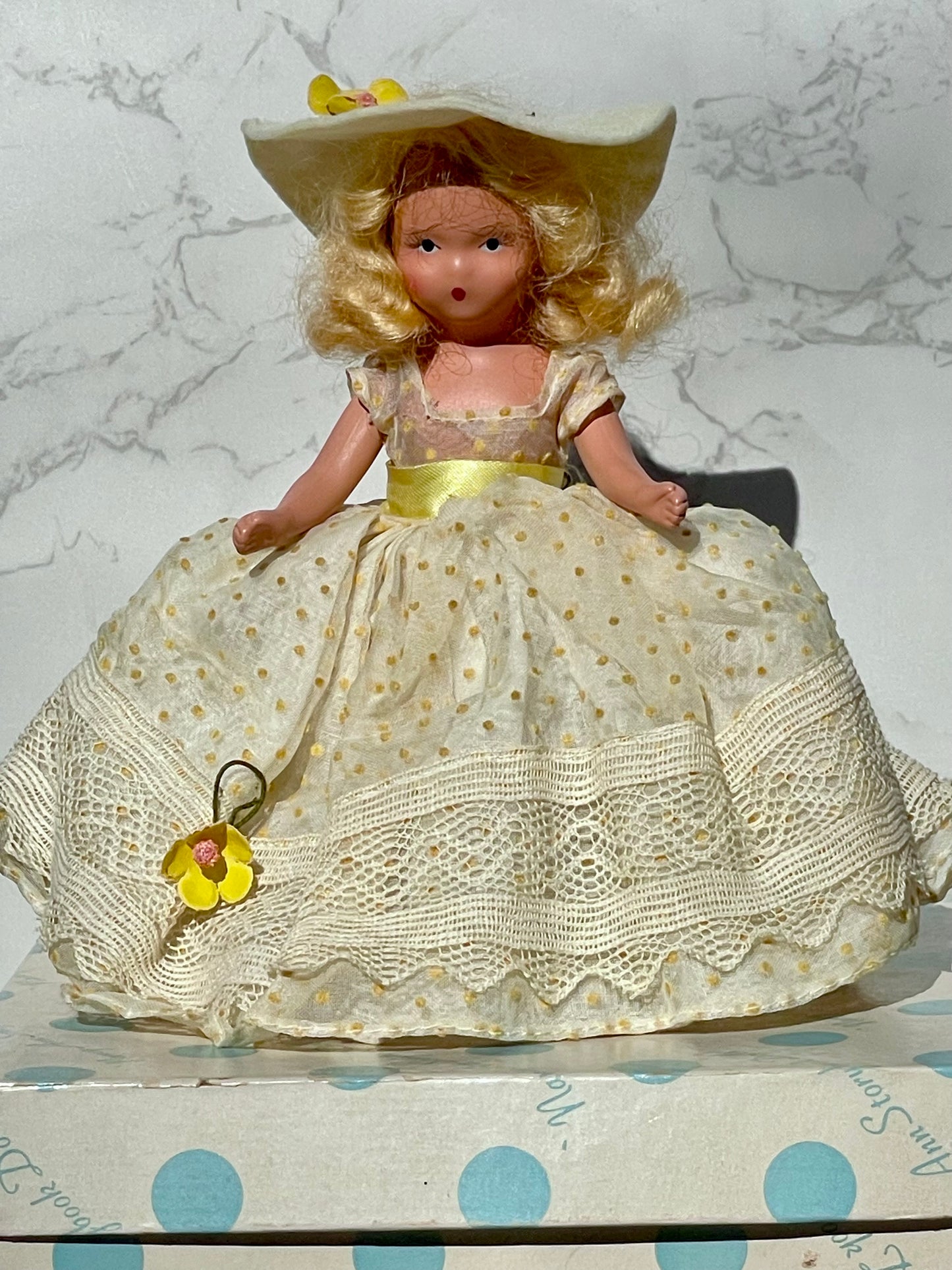 Nancy Ann storybook doll season series 91 summer doll antique collector doll yellow dress blonde hair yellow flower on hat original box frozen legs free shipping antique gift collector gift thebrokenbirdcompany christmas birthday gift for her mothers day 1940s collector doll cream colored box with blue polka dots