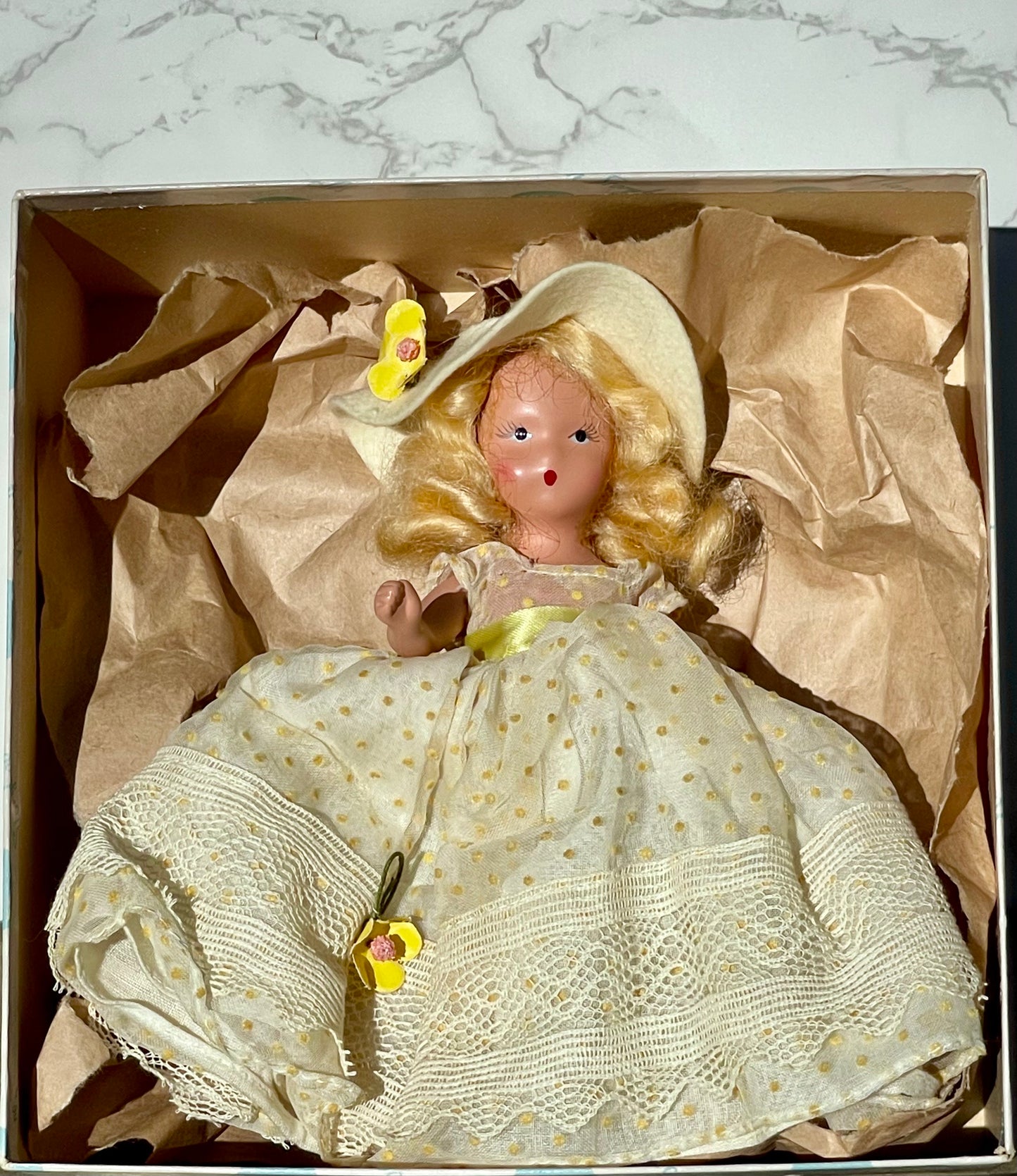 Nancy Ann storybook doll season series 91 summer doll antique collector doll yellow dress blonde hair yellow flower on hat original box frozen legs free shipping antique gift collector gift thebrokenbirdcompany christmas birthday gift for her mothers day 1940s collector doll cream colored box with blue polka dots