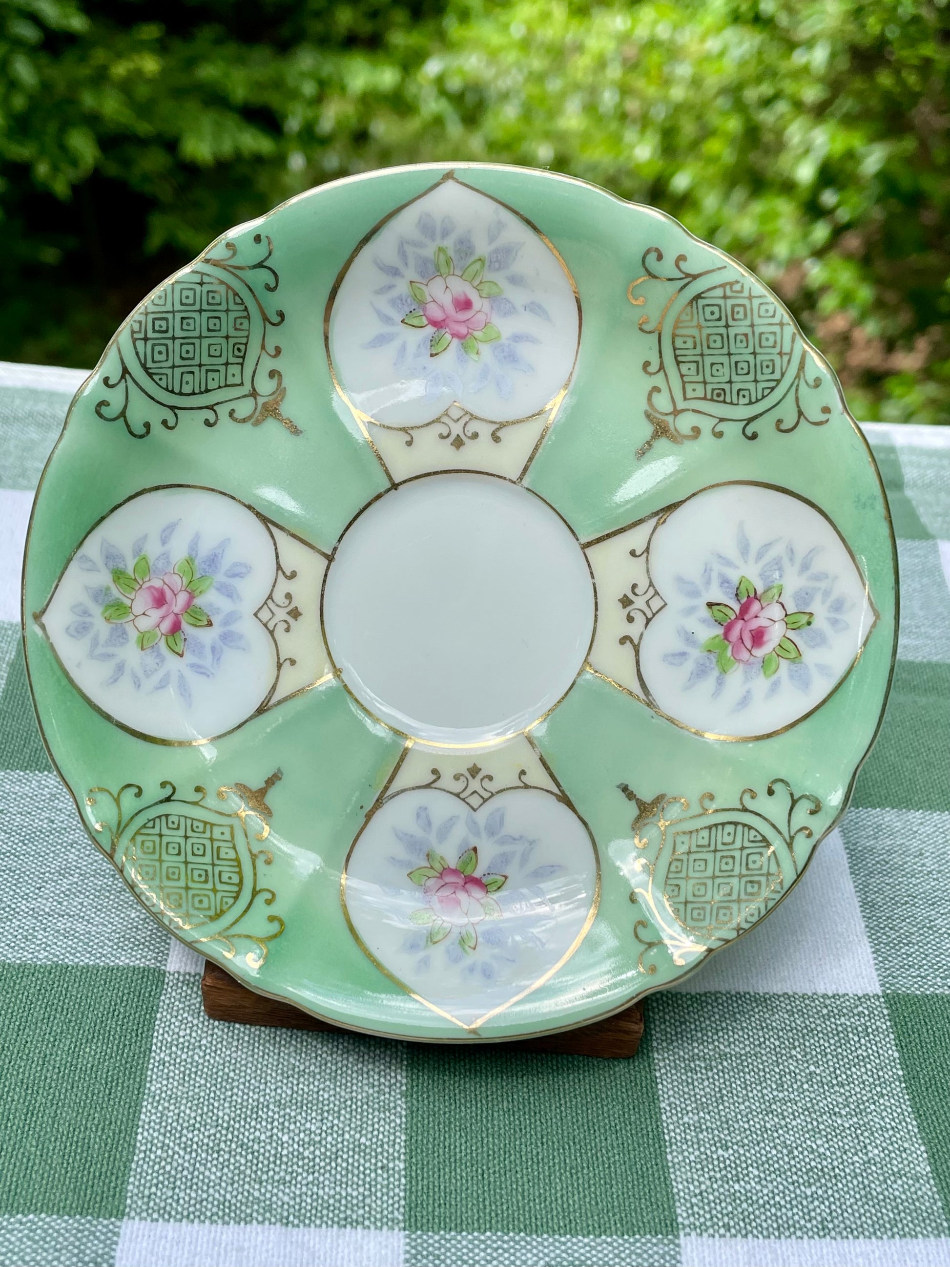 Decorative ceramic plate with floral patterns on a green checkered tablecloth
