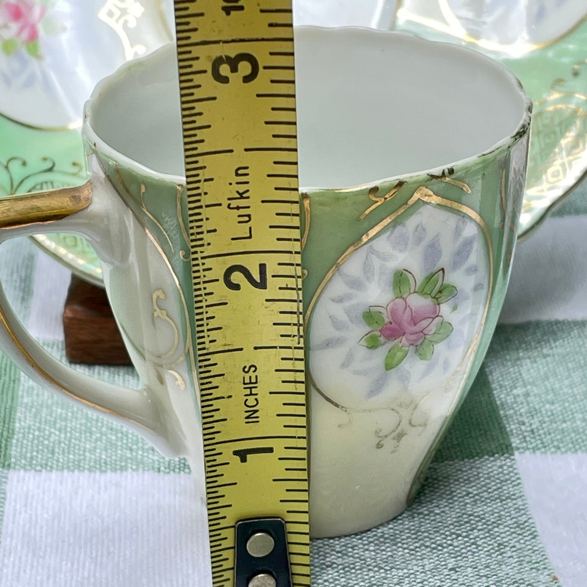 Ceramic cup with floral design and a measuring tape indicating its size. thebrokenbirdcompany home decor kitchenware tea set green and gold pink rose bud